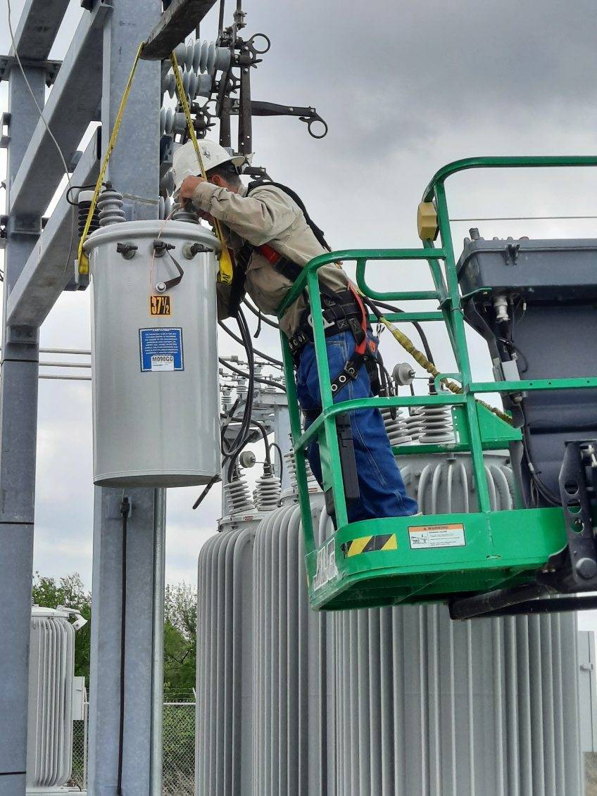Coop3 A man in a cherry-picker working on power lines.