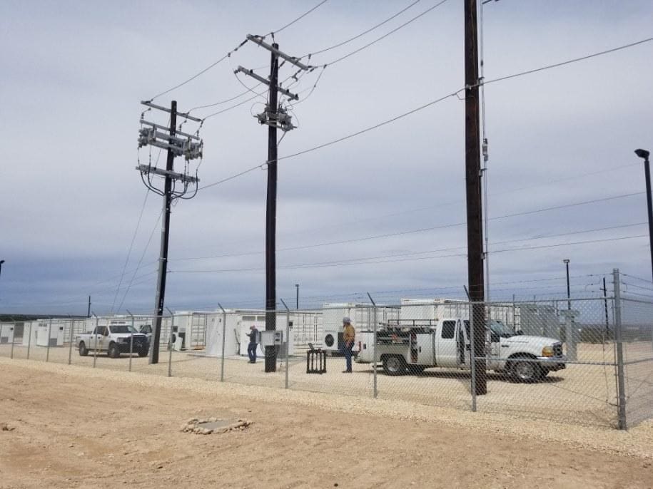 A group of people standing around in front of power lines.