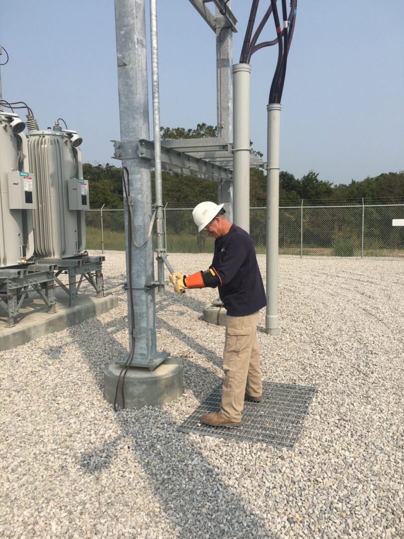 A man in hard hat working on electrical equipment.