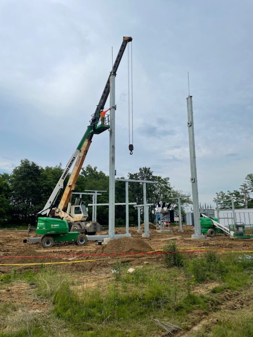 A crane is lifting up the poles to be installed.